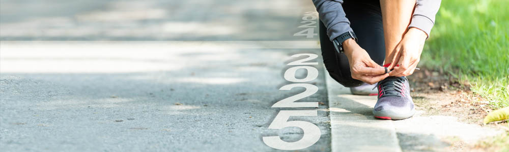 Close-up of person tying their shoe on a road, with the numbers 2025 beside them Close-up of person tying their shoe on a road, with the numbers 2025 beside them
